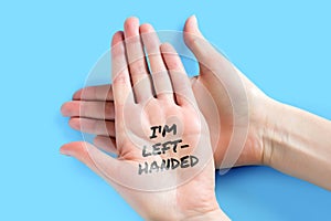 Female left hand with the words I am left-handed  on a blue background