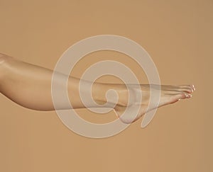 Female leg and foot isolated on beige background