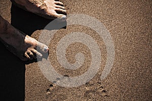 Female legs on a beach. Footprints visible on the sand