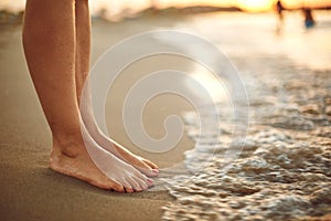 Female legs on the beach sand of the sea.