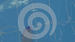 Female legs with a beautiful blue pedicure go along the pool. Blue water in the pool with sunlight reflections