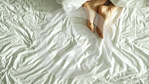 Female legs in bed view from above, white bedding photo