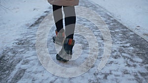 Female legs in black boots dancing in winter path covered snow rear view. Legs of young woman in winter shoes dancing on