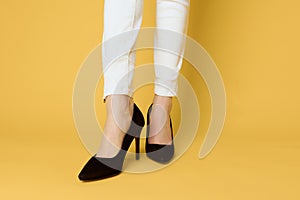 Female legs black shoes fashion attractive look white jeans yellow background