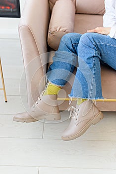 female legs in blue jeance, green socks and beige leather lace-up boots. Indoor photo