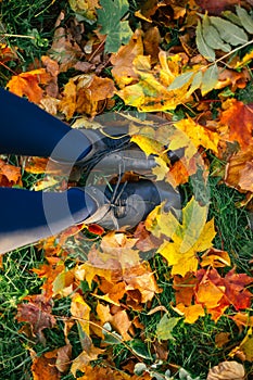 Female legs in boots on ground with autumn leaves