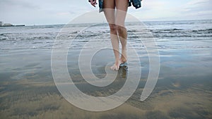 Female legs dancing on a sandy beach. Beautiful woman walking on the beach.