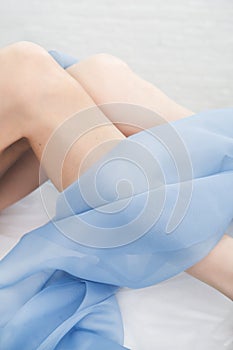 Female legs after depilation, smooth soft skin, woman& x27;s legs covered by light fabric. epilation and body care