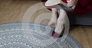 Female legs and feet of an adult woman arriving to sit down and kick off her red, blue and white high heels