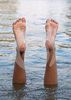 Female legs and feet upside down in the water