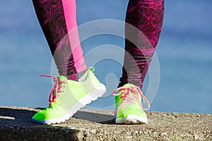 Female legs feet in vivid color yellow shoes on seaside