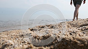 Female legs and feet walking along the sandy beach