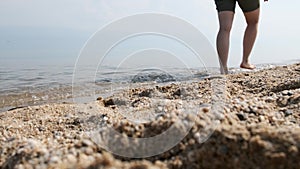 Female legs and feet walking along the sandy beach. Slow motion