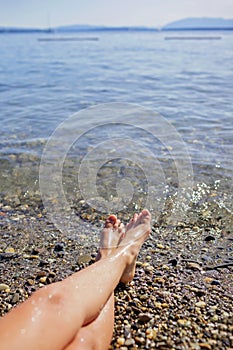 Female legs, a girl is sunbathing on pebble beach of Geneva Lake, summer vacations and travel