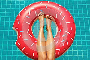 Female legs and inflatable swim ring in shape of donut