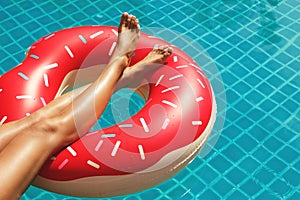 Female legs and inflatable swim ring in shape of donut