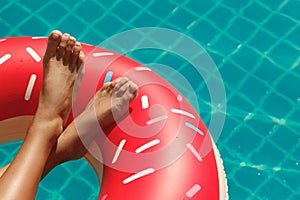 Female legs and inflatable swim ring in shape of donut