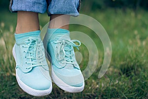 Female legs in jeans and sport shoe floating in the air above th