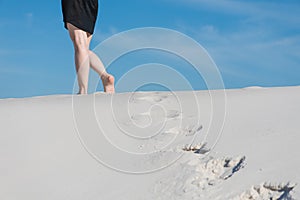 Female legs and prints on white sand