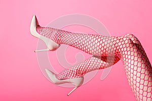 Female legs raised in sexy pink fishnets and high heels