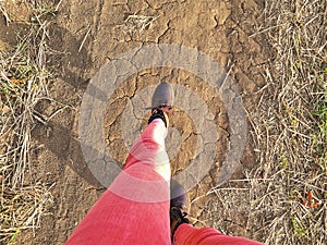 Female legs in red jeans on the soil rural road