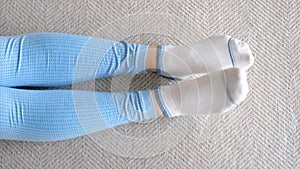 Female legs in socks bend and unbend feet, home workout concert, top view.