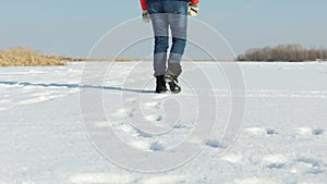 Female legs walk on snow. Woman in winter boots go along snowy field. Trample footprints in white snow, outdoors walking