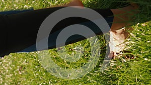 Female legs walking on fresh green grass. Vertical video. Yoga outdoors