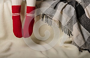 Female legs in warm white knitted tights and red socks on a whit