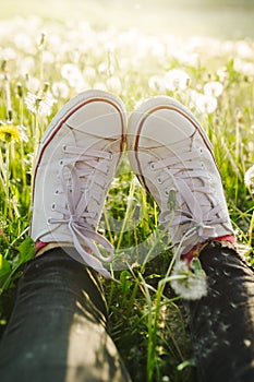 Female legs in white canvas sneakers and black jeans