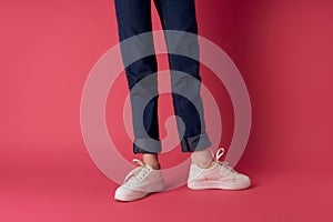 female legs in white sneakers upside-down view pink background fashion