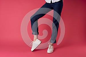 female legs in white sneakers upside-down view pink background fashion