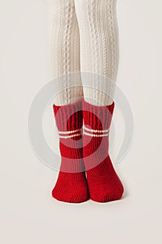 Female legs in white stockings and red knit socks.