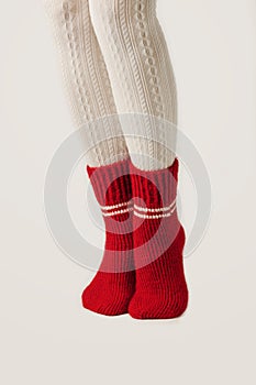 Female legs in white stockings and red knit socks.