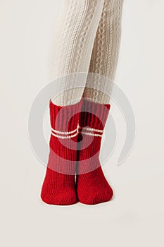 Female legs in white stockings and red knit socks.