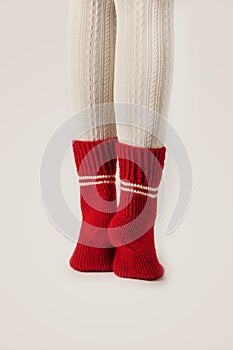 Female legs in white stockings and red knit socks.