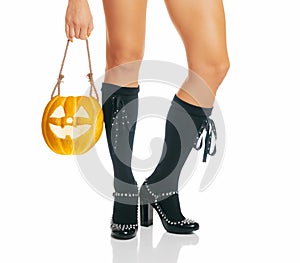 Female legs of witch and Halloween jack-o-lantern pumpkin.