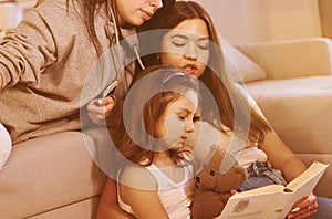 Female lesbian couple with little daughter spending time together at home