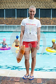 Female lifeguard holding rescue can at poolside