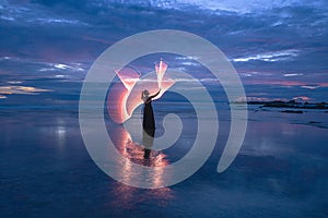 Female light painting model on sandy Tanjung Layar Beach during beautiful dark blue sunrise photo