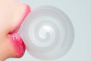 Female lips blowing pink bubble gum. Closeup of a woman face with pink lips and gum bubble. emale lips holding shiny