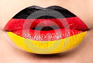 Female lips close up with a picture flag of Germany. black, red, yellow.