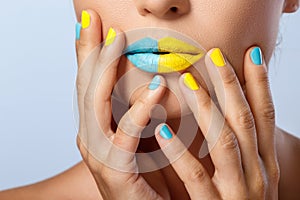 Female lips with two different lipsticks and colorful nails