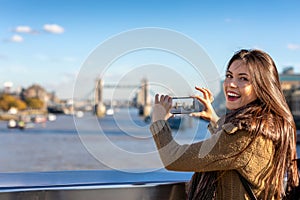 Female London tourist is taking pictures of the Tower Bridge