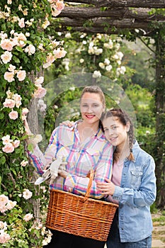 female with long curly hair and girl standing near roses flower outdoors