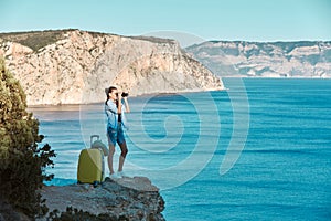 Female looking in binoculars on ocean. Seascape view and mountain. Business travel and new ground concept, copy space