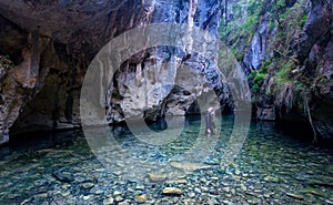 Female looks up in awe admiring the canyon walls and caves high above her