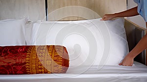Female maid setting up white pillow in hotel