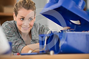 Female maintenance engineer testing voltage with digital multimeter