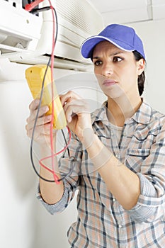 female maintenance engineer testing voltage with digital multimeter